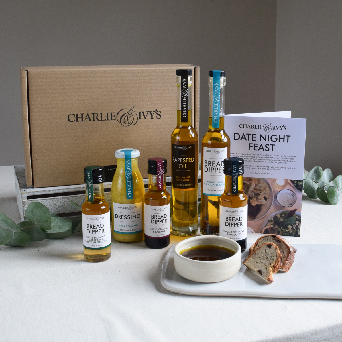 A collection of products from the date night feast box alongside a dipping bowl and bread