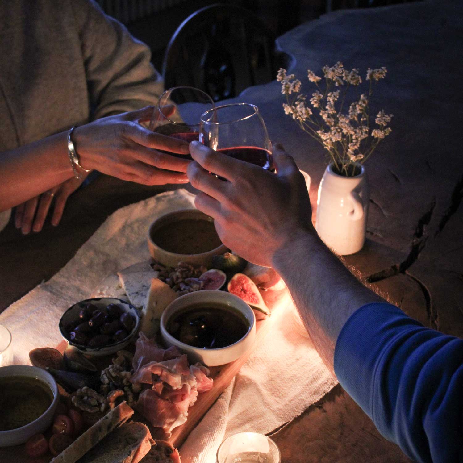 Hands holding glasses of wine over a sharing platter