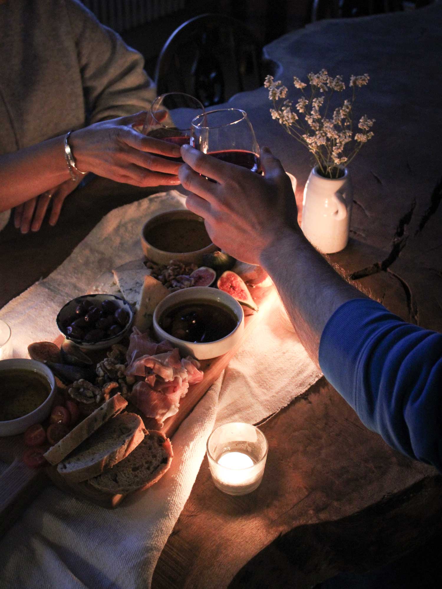 an evening sharing board with two hands holding glasses of wine