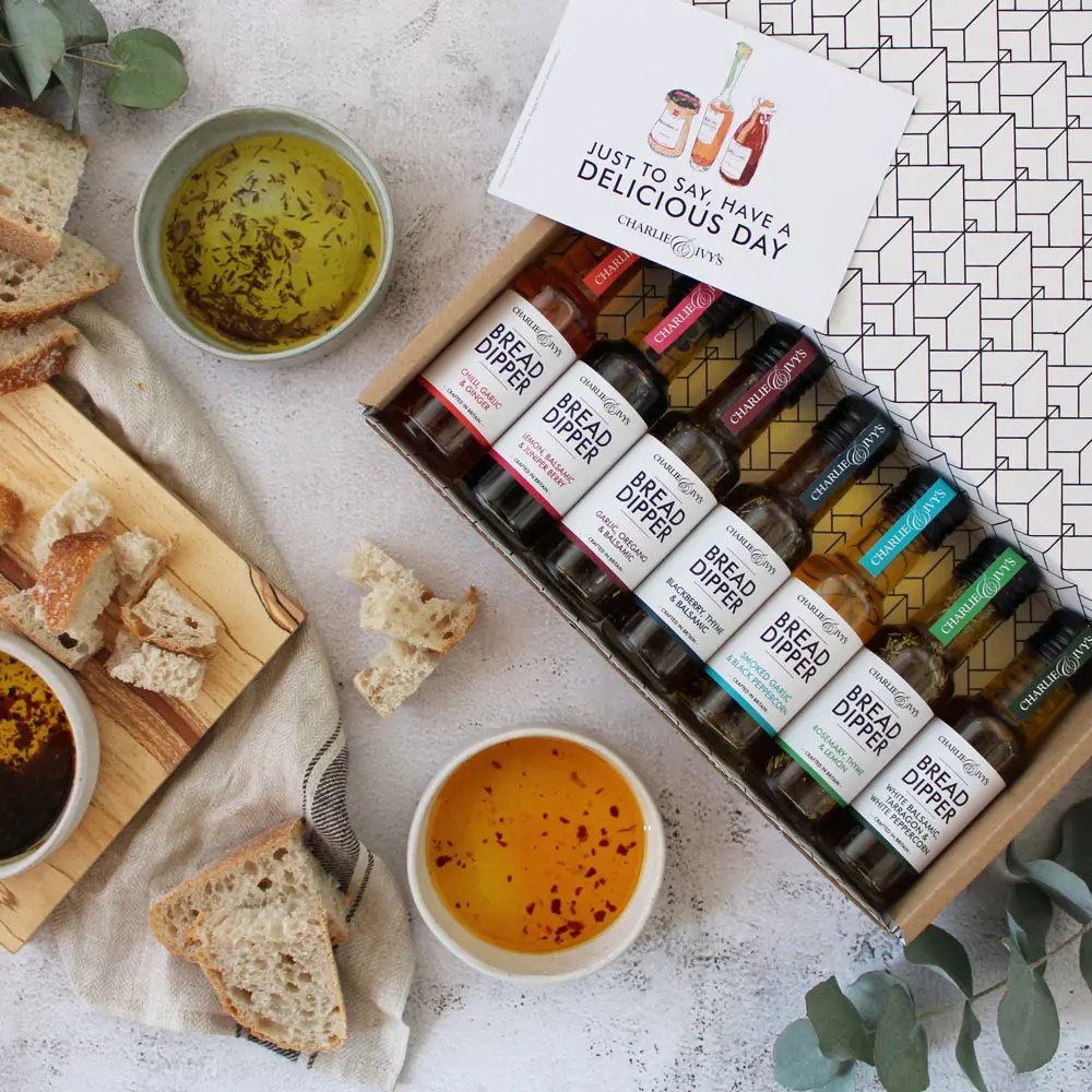 An open gift box featuring 7 mini bread dippers, alongside dipping bowls and bread